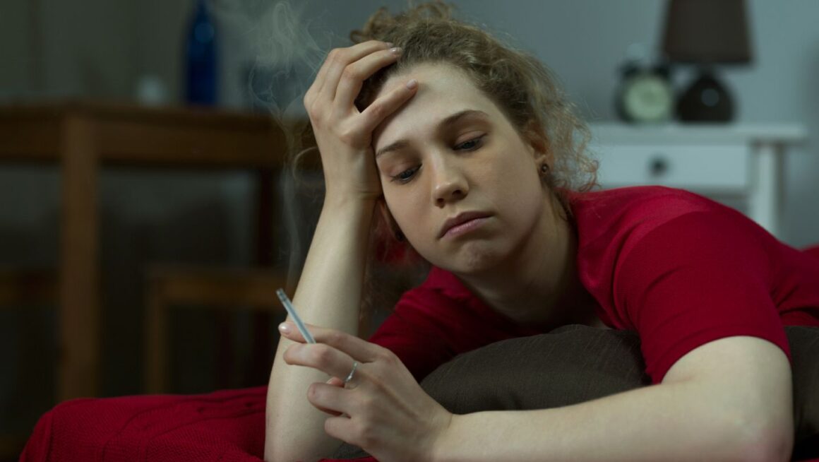 a woman lying in bed holding a hemp leaf